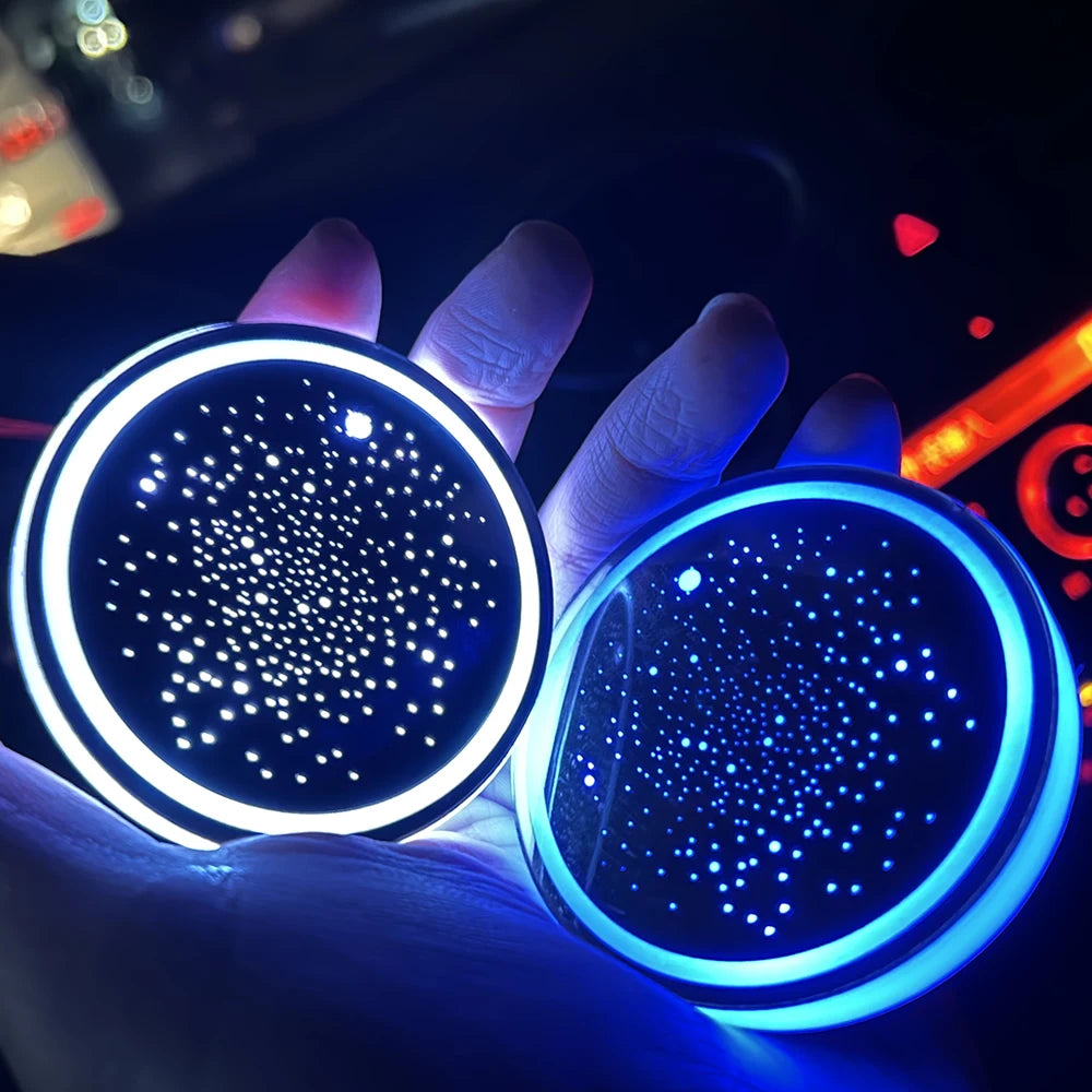 A hand holds a glowing blue LED cup holder light, illuminating the interior of a car.