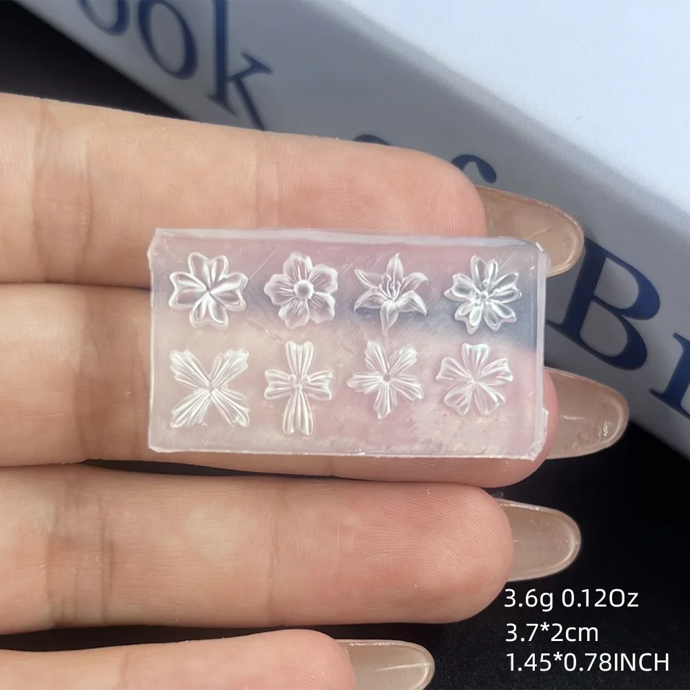A hand holds a clear silicone mold with floral nail art designs on it.
