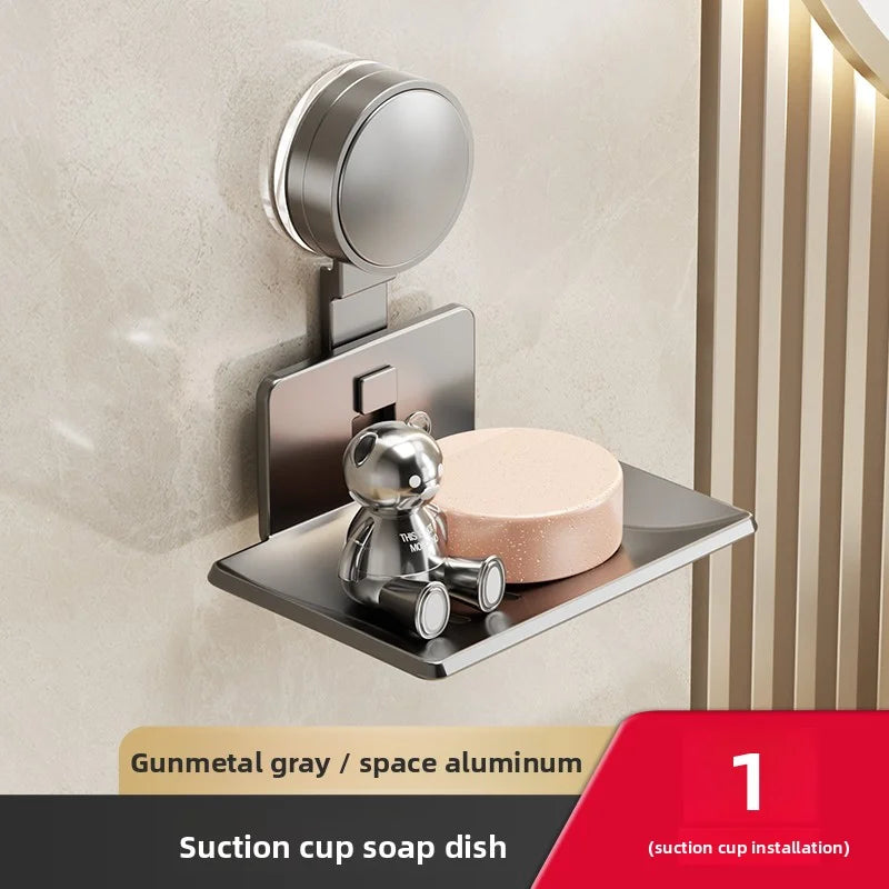 A silver wall-mounted suction cup soap dish with a bear figurine installed on a beige wall.