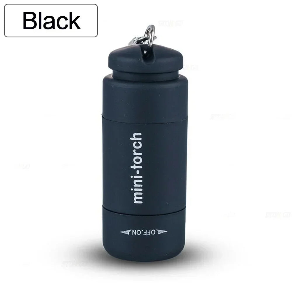 A black mini-torch keychain flashlight is shown against a white background.