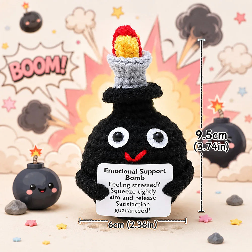 A black crochet bomb shaped like a face with red eyes and a yellow top, displayed on a light surface.