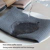 A close-up of a gray cotton waffle weave towel being used to absorb water on a white plate.