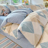 A set of light blue and beige patterned cotton duvet covers and pillow shams displayed on a bed.