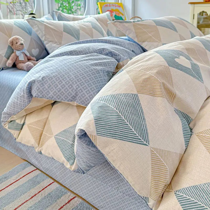 A set of light blue and beige patterned cotton duvet covers and pillow shams displayed on a bed.