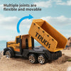 A yellow toy truck with an open bed is shown on sand, demonstrating flexible joints.