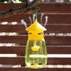 A yellow fruit fly trap kit with a pheromone lure suspended from a branch.