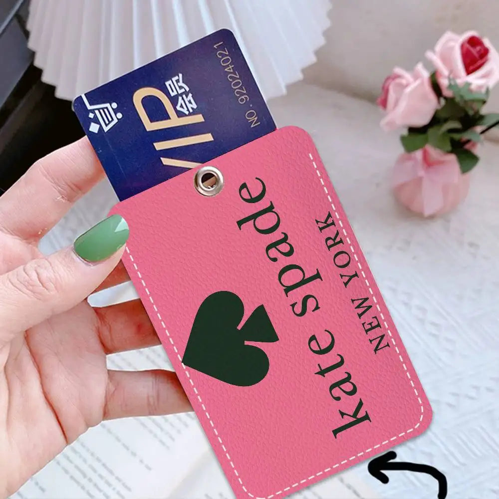 A pink card holder with a green spade design and gold lettering is held by a hand against a white background.