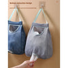 A gray mesh garbage bag holder is shown hanging on a wall, designed for bottom extraction.