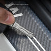 A close-up of a metal door sill protector sticker being applied to a textured surface.