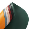 A stack of colorful, reversible non-slip placemats showing various shades of green, brown, orange, and beige.