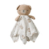 A soft brown teddy bear stuffed animal wearing a light gray comforter with small brown bear patterns.