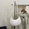 A white textured leather crossbody bag with adjustable straps is displayed on a hanger against a light background.
