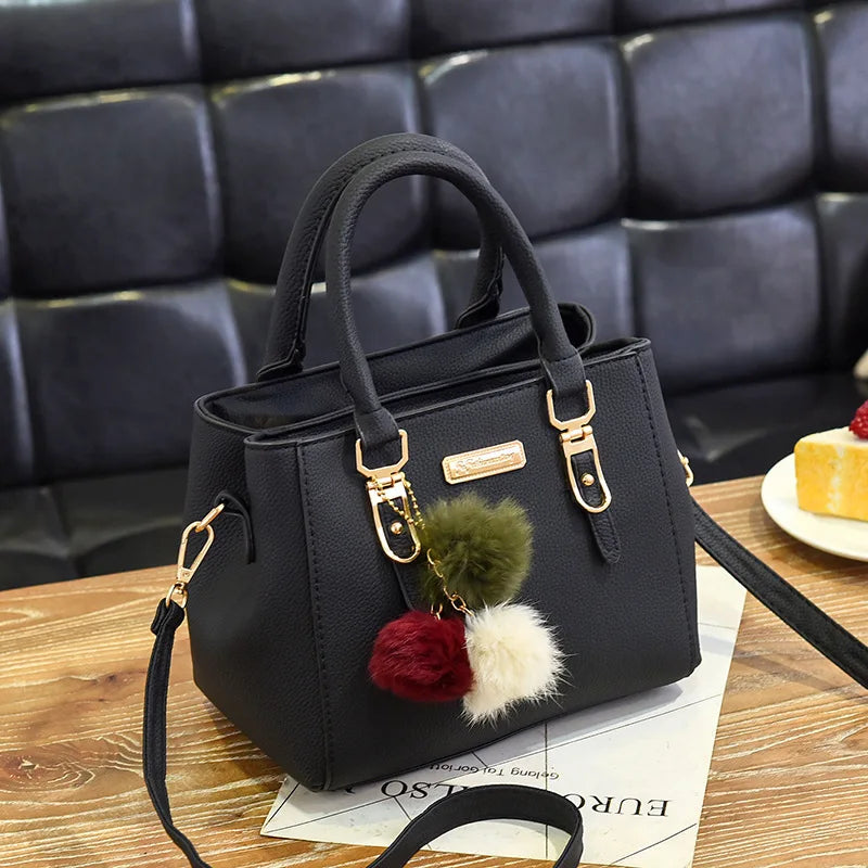 A black vintage PU leather tassel shoulder bag with a gold hardware detail resting on a wooden surface.