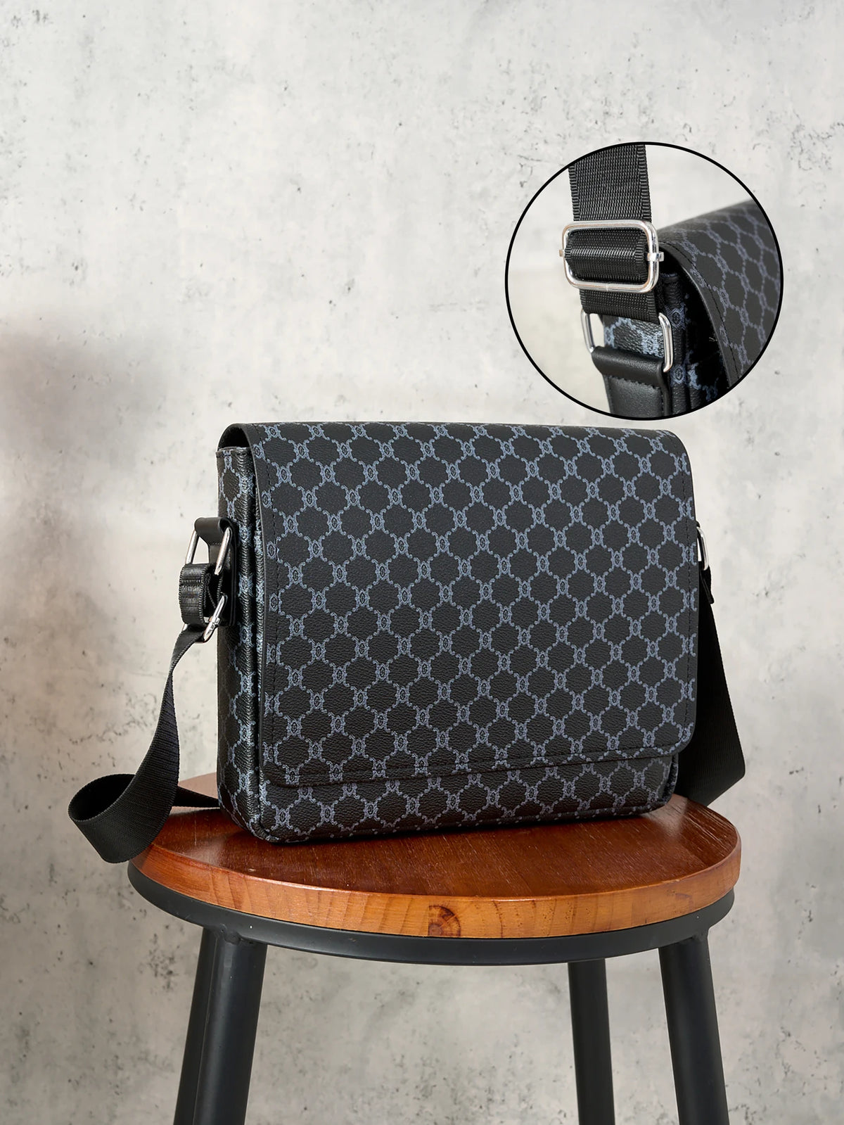 Black patterned crossbody bag displayed on a wooden stool with an inset showing the strap detail.