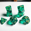 A set of seven translucent green acrylic polyhedral dice scattered on a white surface.