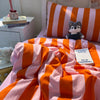 Orange and pink striped duvet cover set with pillowcases featuring a teddy bear plush toy.