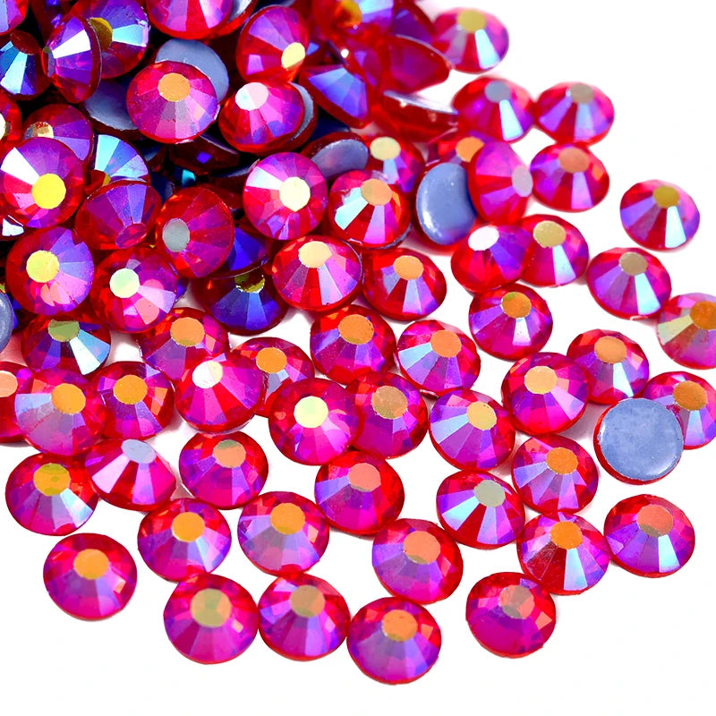A close-up view of numerous small, faceted red and purple rhinestones scattered on a white background.