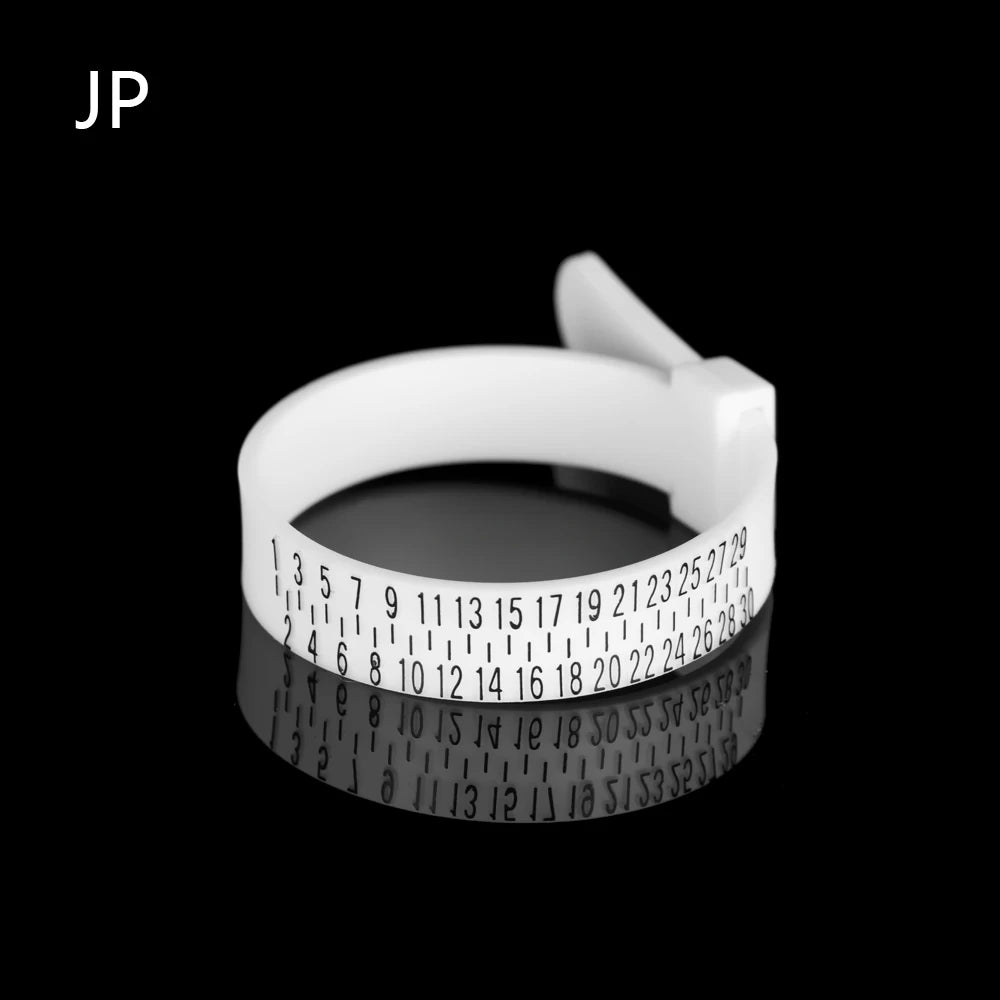 A white ring sizer measuring tool with a magnified scale is shown against a black background.