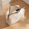A white lace mesh makeup bag with a black trim is shown open, containing a cosmetic product and a brush on a wooden surface.