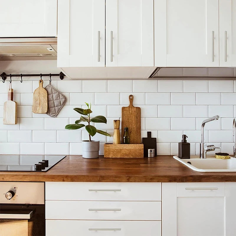 Küchenarbeitsplatte mit Holz-Cutting Boards, Spüle und weißen Schränken mit gebürstetem Nickel und goldenen Griffen