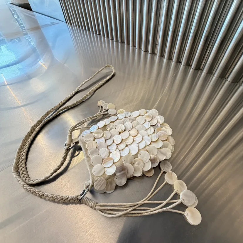 A beige chain shoulder bag decorated with round, iridescent white sequins.
