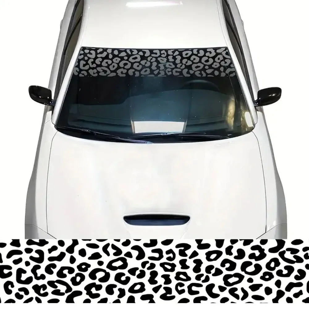 A white car windshield covered with a leopard print sunshade decal strip.