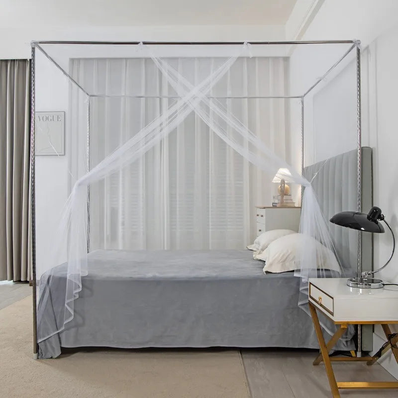A full bed draped with a sheer white lace canopy mosquito net in a modern bedroom setting.
