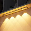 A modern cabinet light fixture with multiple LED lights illuminating a textured wall surface.