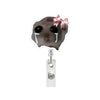 A cute hamster face charm with teary eyes and a pink bow attached to a retractable badge reel.