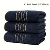 Three navy blue bath towels with gold stripes stacked neatly.