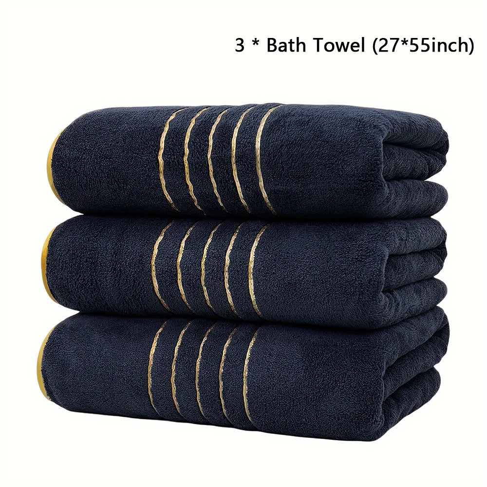 Three navy blue bath towels with gold stripes stacked neatly.