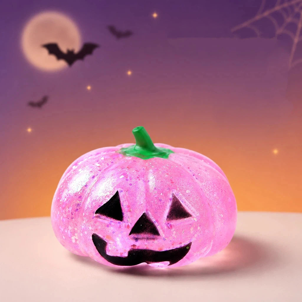 Leuchtender pinker Halloween-Kürbis-Fidget-Spielzeug mit geschnitztem Gesicht vor lila-orangefarbigem Hintergrund mit fliegen