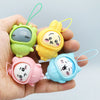 A hand holds four small PVC bag pendant dolls in shades of green, yellow, pink, and blue.