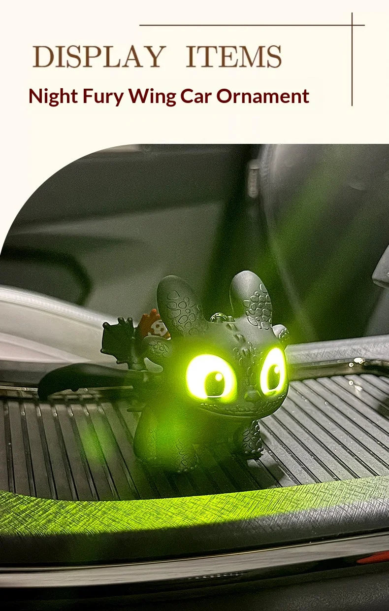 A glowing green Toothless car ornament with movable wings displayed on a car interior surface.