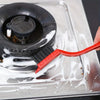 A red kitchen cleaning brush and scraper tool is used to clean food residue from a metal cooking surface.