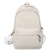 A beige waterproof nylon laptop backpack with a white bear charm attached to the zipper.