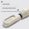 A close-up view of a beige fully automatic hook umbrella with a large surface and a light-colored handle.