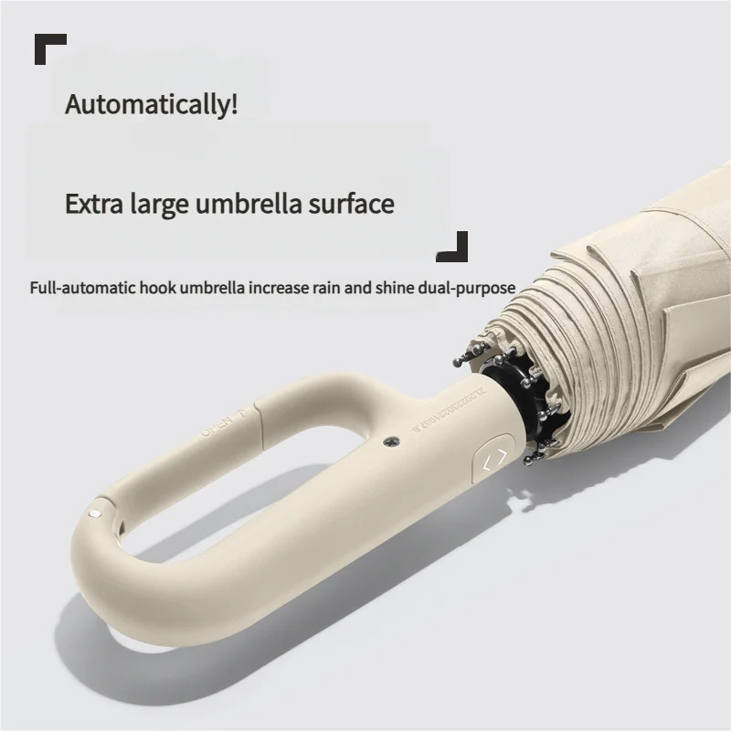 A close-up view of a beige fully automatic hook umbrella with a large surface and a light-colored handle.