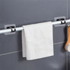 A white textured towel is hanging on a silver curtain rod with adhesive brackets against a gray tiled wall.