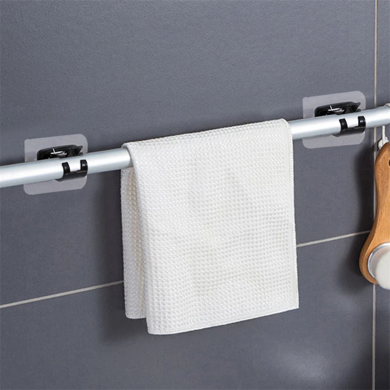 A white textured towel is hanging on a silver curtain rod with adhesive brackets against a gray tiled wall.