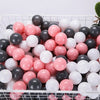 A white and pink ball pit filled with various sized black, white, and pink plastic balls for toddlers.