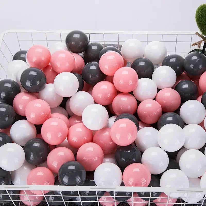 A white and pink ball pit filled with various sized black, white, and pink plastic balls for toddlers.