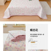 Pink and purple floral quilted bedspread with a delicate pattern shown on a bed.