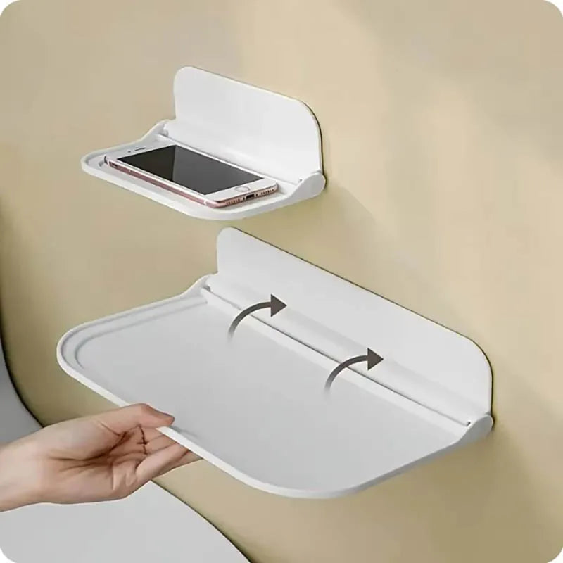 A white foldable no-drill wall shelf is shown with a phone placed inside, demonstrating its space-saving storage function.