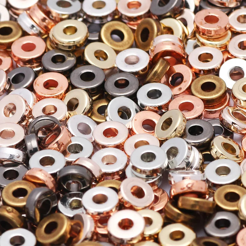 A close-up view of small round acrylic spacer beads in various gold and silver tones for jewelry making.