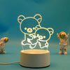 A glowing white silhouette of a bear hugging a smaller bear, displayed on a round LED night light base.