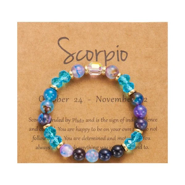 Perlenarmband mit violetten und blauen Kristallen, präsentiert auf einer braunen Karte mit dem Skorpion-Zeichen.