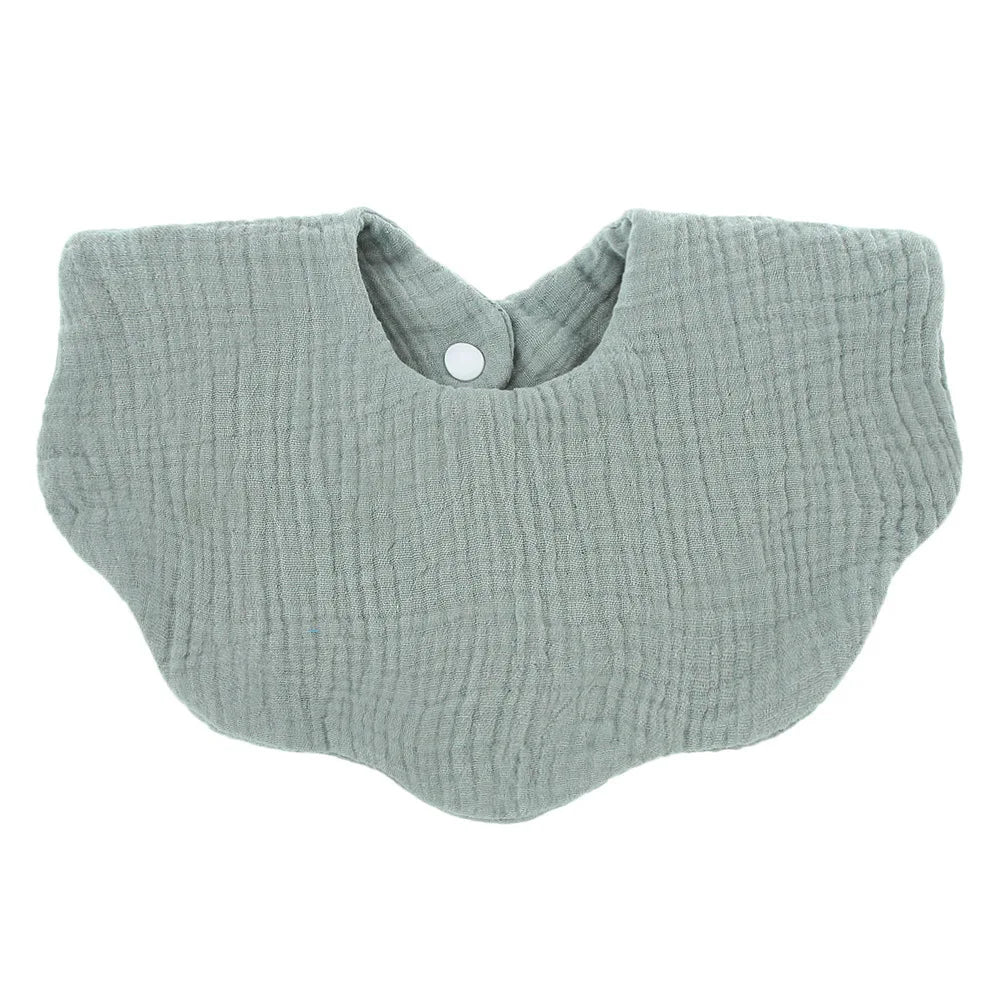 A light sage green soft cotton baby bib in a bandana style with a rounded neckline.