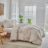A beige three-dimensional pleated floral duvet cover set displayed on a bed in a bright, minimalist room.