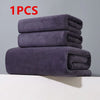 A stack of three dark gray microfiber bath towels on a white surface.